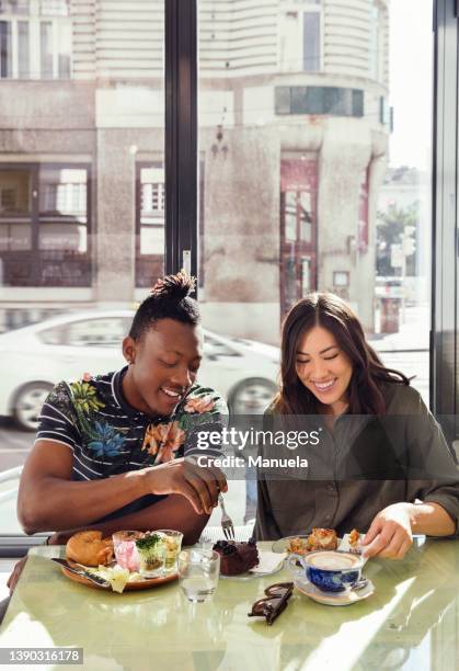 smiling couple enjoying breakfast in restaurant - enjoying coffee cafe morning light stock pictures, royalty-free photos & images