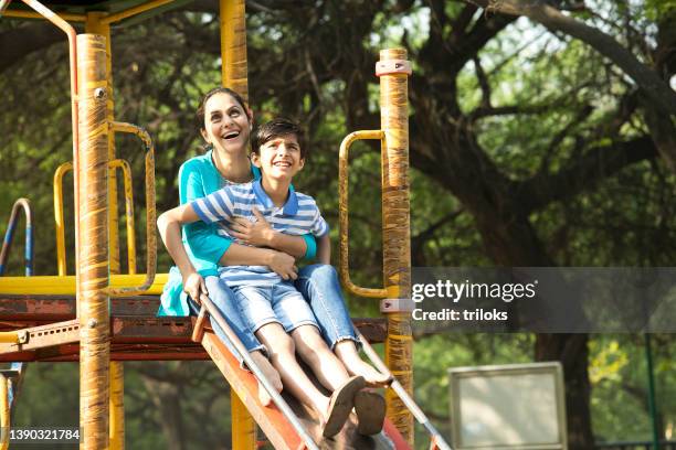 mother with son having fun on slide at playground - sliding stock pictures, royalty-free photos & images