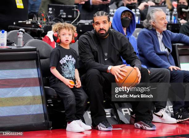 Drake sits with his son Adonis before the Toronto Raptors play the Philadelphia 76ers in their basketball game at the Scotiabank Arena on April 7,...