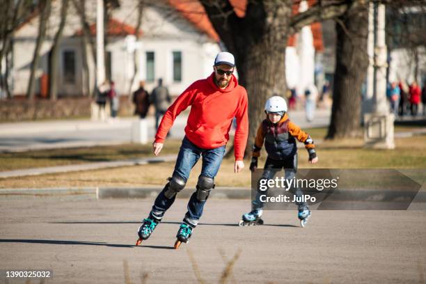 padre e hijo patinando juntos en un parque público - patín en línea fotografías e imágenes de stock