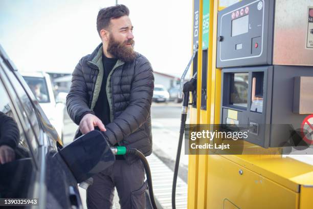 when it was his turn, the man refueled at the gas station. isl - gas tank stock pictures, royalty-free photos & images