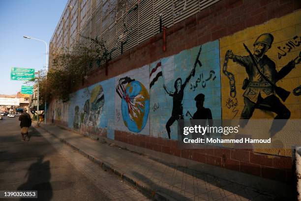 Yemeni man walks near graffiti drawn by activists previously against Saudi Arabia, on the wall of the Saudi embassy on April 08, 2022 in Sana'a,...