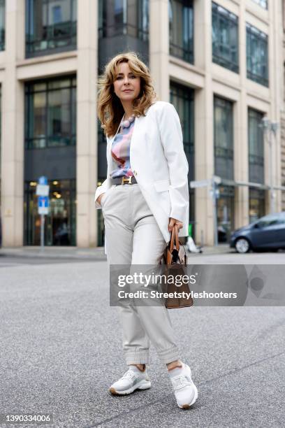 German TV host Bettina Cramer wearing a white blazer by Vero Moda, a multicolored blouse by Vero Moda, light grey pants by Object, white sneaker by...