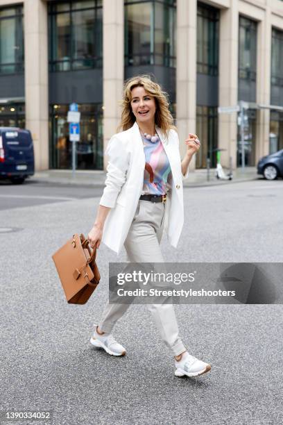 German TV host Bettina Cramer wearing a white blazer by Vero Moda, a multicolored blouse by Vero Moda, light grey pants by Object, white sneaker by...