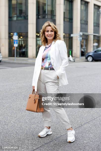 German TV host Bettina Cramer wearing a white blazer by Vero Moda, a multicolored blouse by Vero Moda, light grey pants by Object, white sneaker by...