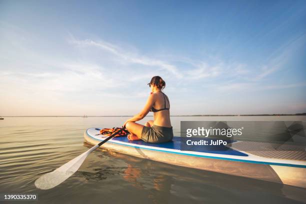 young woman swimming on sup boards alone at sunset - using a paddle stock pictures, royalty-free photos & images