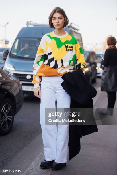 Brazilian model Rayssa Medeiros wears a yellow and green floral "ideal spot" sweater, white jeans, black boots after the Louis Vuitton show at Musée...