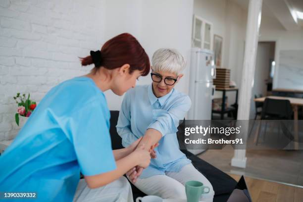 female medical professional examining a senior patient - huidaandoening stockfoto's en -beelden