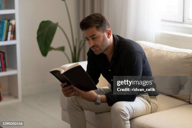 young man relaxing reading book - open bible stock pictures, royalty-free photos & images