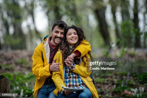 happy affectionate couple in raincoats enjoying in nature - rain kiss stock pictures, royalty-free photos & images