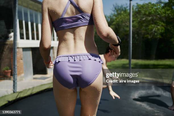 girl standing on a trampoline watching the other boys jump on it - bending over backwards stock pictures, royalty-free photos & images