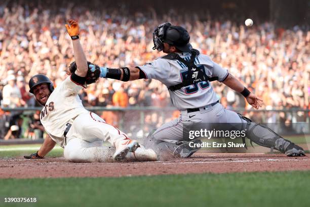 Darin Ruf of the San Francisco Giants slides safely past Jacob Stallings of the Miami Marlins to score the winning run on a hit by Austin Slater in...