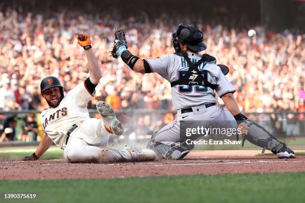 Darin Ruf of the San Francisco Giants slides safely past Jacob Stallings of the Miami Marlins to score the winning run on a hit by Austin Slater in...