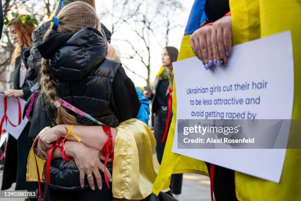 Mother and. Daughter hug near a protestor holding a sign during a flash mob style silent protest against the ongoing Russian invasion of Ukraine in...