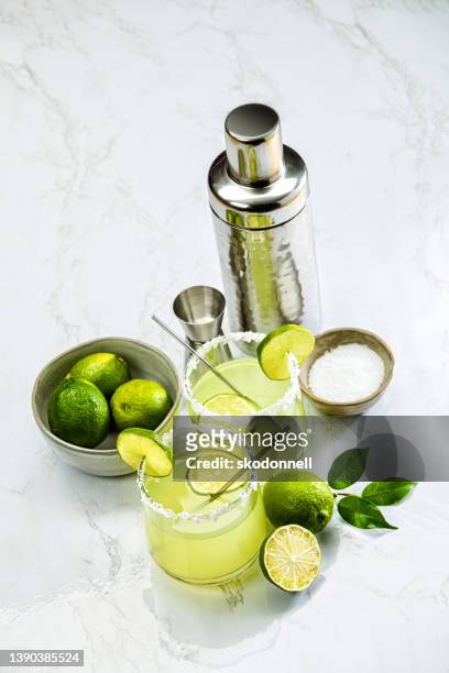 margarita glass with mixer and limes on a white marble background - cinco de mayo background stock pictures, royalty-free photos & images