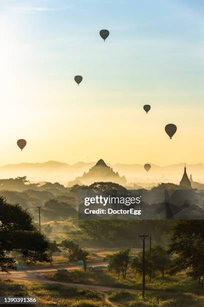 tourist sightseeing balloons flying over dhammayangyi pagoda temple at sunrise, bagan, myanmar - bagan stock-fotos und bilder