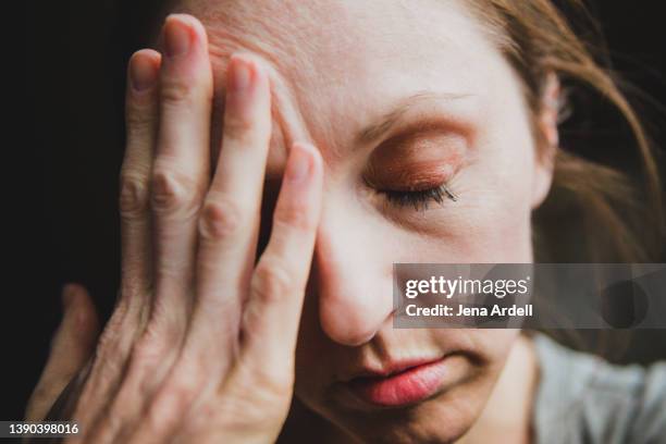 woman with headache overwhelmed by stress, anxiety, or depression - cansado fotografías e imágenes de stock