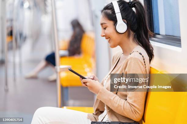 young woman listening the music when travelling by subway - consumer journey stock pictures, royalty-free photos & images