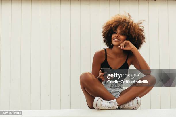 pretty young afro woman using phone - curly hair isolated stock pictures, royalty-free photos & images