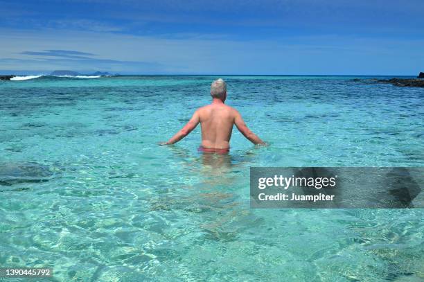 lonely young man enjoys a day of sun and beach at caleta del mero beach, lanzarote - white bay stock pictures, royalty-free photos & images