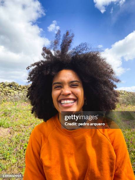 young afro brazilian woman smiling naturally in nature - black woman hair stock-fotos und bilder