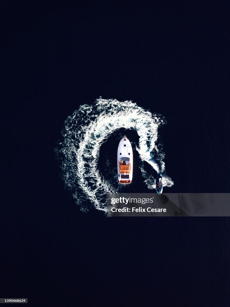 Aerial view of a jet ski swirling around a recreational boat.
