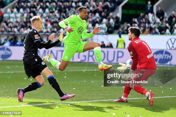 Lukas Nmecha of VfL Wolfsburg shoots under pressure from Amos Pieper and Stefan Ortega of DSC Arminia Bielefeld during the Bundesliga match between...