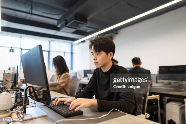 male white-collar worker sitting in front of the computer in the office and working hard - desktop pc ストックフォトと画像
