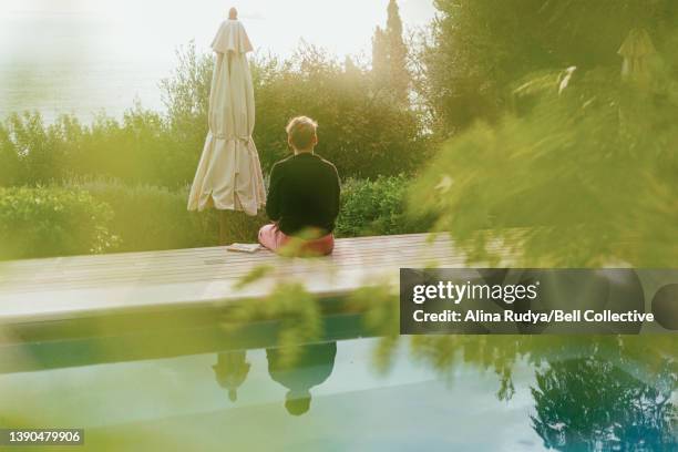 Young man reading a book by the pool