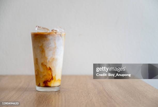 an iced latte on table with white wall background. - coffee and milk stock pictures, royalty-free photos & images