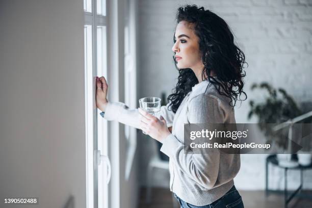 schöne junge frau trinkt zu hause ein frisches glas wasser - wasser trinken büro stock-fotos und bilder