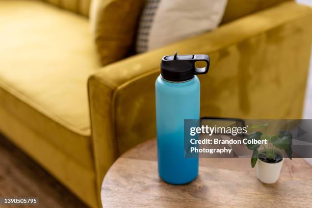 blue and teal water bottle on coffee table - reusable water bottle - fotografias e filmes do acervo