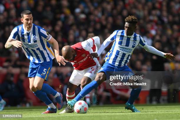 Yves Bissouma and Lewis Dunk of Brighton & Hove Albion battles for possession with Alexandre Lacazette of Arsenal during the Premier League match...