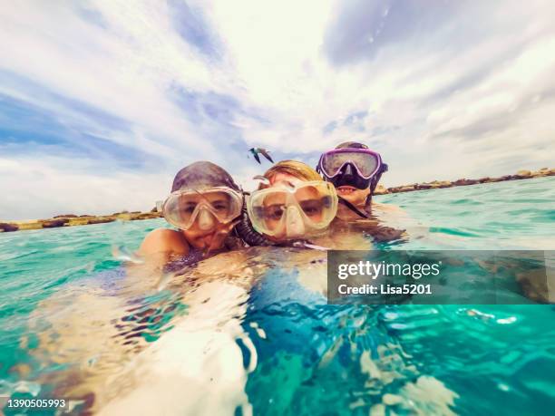 madre e hijas con máscaras de snorkel nadando juntas en el mar caribe en una aventura familiar épica - curaçao fotografías e imágenes de stock