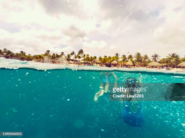 two young girls swimming in the ocean underwater in crystal blue caribbean sea - curaçao stock pictures, royalty-free photos & images
