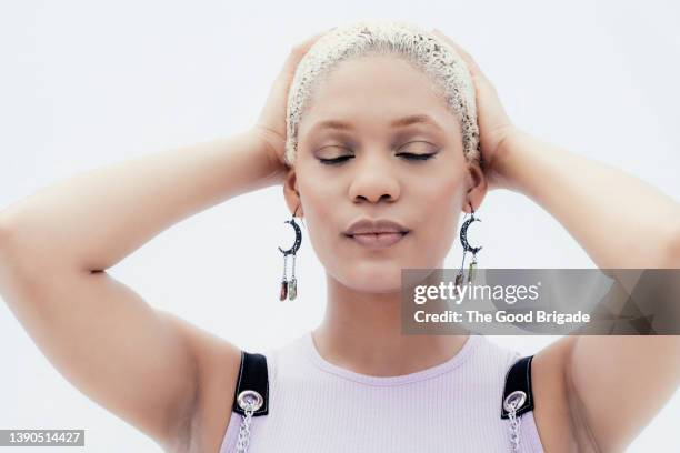 portrait of beautiful woman with eyes closed and hands on head - bleached hair stock-fotos und bilder