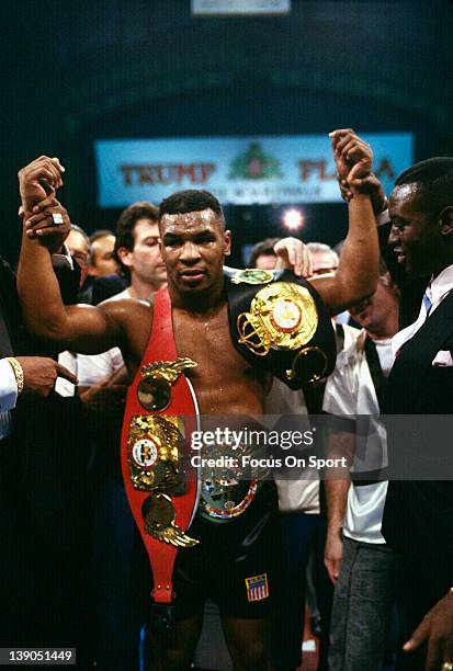 Heavyweight fighter Mike Tyson wears the championship belts after a fourth round TKO of Larry Holmes of a scheduled twelve round WBC, WBA, IBF...