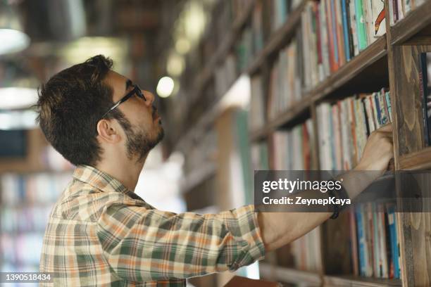 young man looking books at the bookshelves - knowledge is power stock pictures, royalty-free photos & images