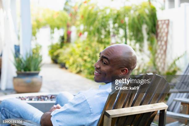 african-american man sitting on adirondack chair on patio - jacksonville beach stock pictures, royalty-free photos & images