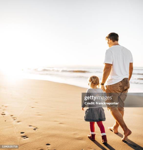 papa und tochter spazieren am strand - vatertag stock-fotos und bilder