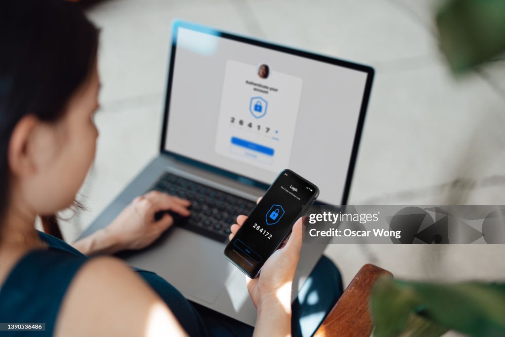 Businesswoman using laptop and mobile phone logging in online banking account