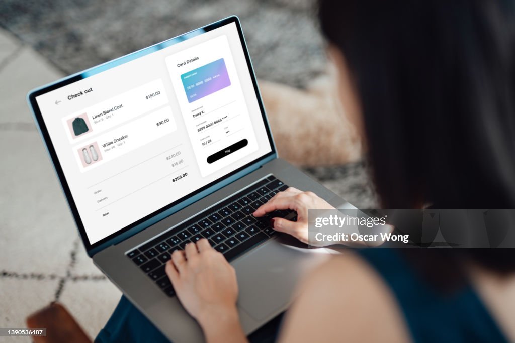 Woman shopping clothes online on laptop and making payment with credit card