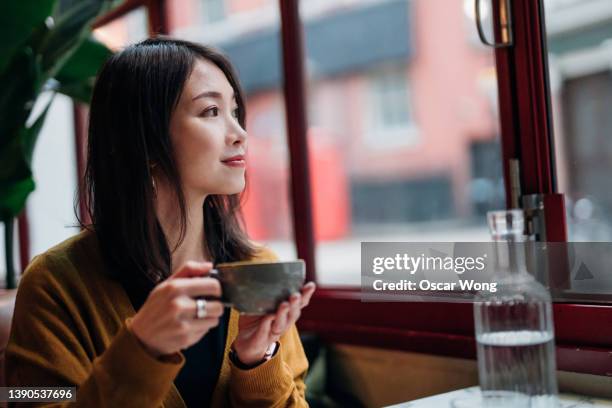young woman enjoying a coffee break at cafe - コーヒー　日本人 ストックフォトと画像