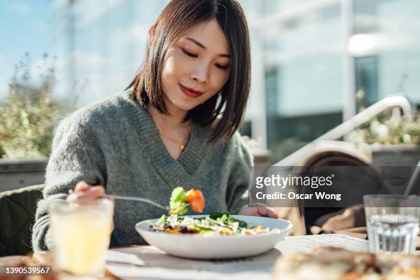 young woman enjoying a vegan lunch at outdoor restaurant - japanese restaurant foto e immagini stock