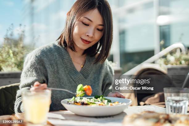 young woman enjoying a vegan lunch at outdoor restaurant - meal ストックフォトと画像