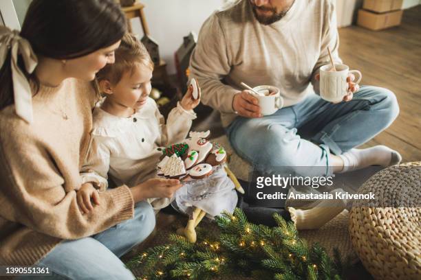 mother, father and her child daughter are drinking warm cacao with christmas gingerbread cookies. - christmas dessert stock pictures, royalty-free photos & images