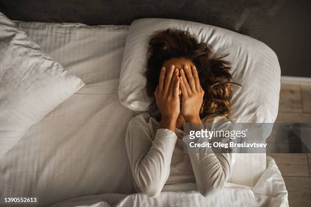 woman in depression closed face with hands and crying in bed. melancholy mood, mental health. life problems - relationship difficulties stock pictures, royalty-free photos & images