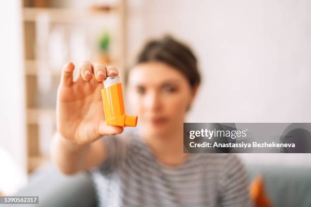 girl holding an inhalation can in her hand - inhalador-preventivo-del-asma fotografías e imágenes de stock