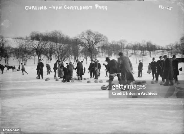 View of a group of men, participating in the sport of curling, possibly on Van Cortlandt Lake in New York's Van Cortlandt Park, early twentieth...