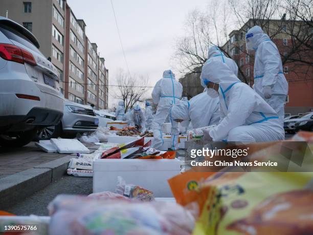 Staff members wearing personal protective equipment sort out food supplies before distributing them to residents under home quarantine on April 9,...